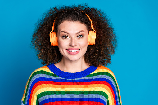 Photo portrait of attractive young woman listen headphones cheerful wear trendy rainbow print clothes isolated on blue color background.