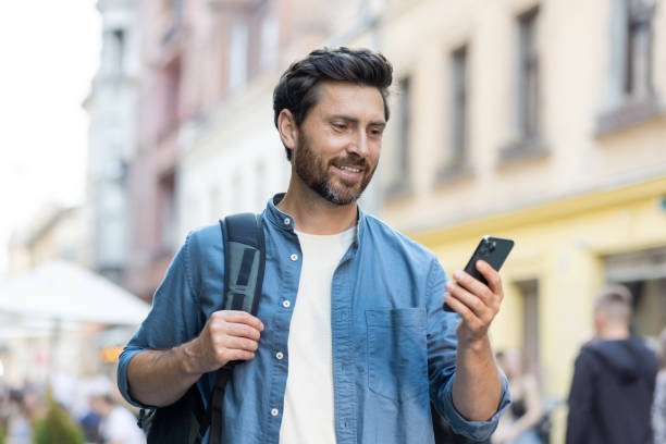 istock Bearded mature man using smartphone while walking in city at evening 2030373565