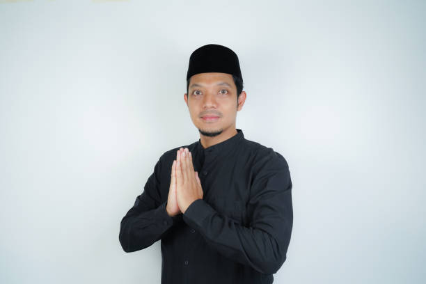 istock Happy smiling Asian Muslim man standing with Eid greeting gesture and welcoming Ramadan isolated background 2030378048