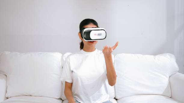 istock Young woman using virtual reality VR goggle at home for vivancy online shopping experience. The virtual reality VR innovation optimized for female digital entertainment lifestyle. 2030385459