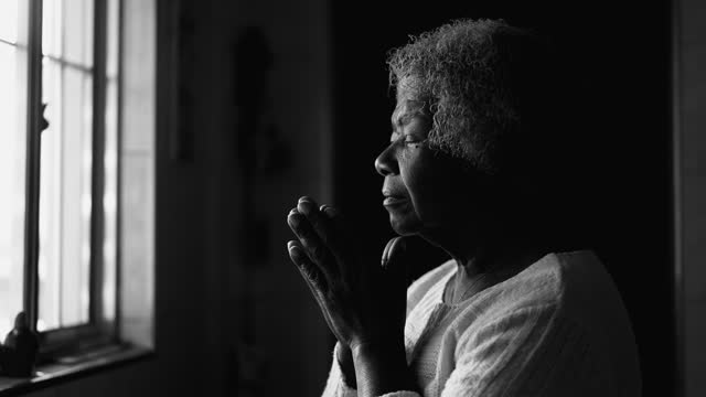Spiritual African American Elderly Lady in Deep Meditation, Black and White Home Prayer by window