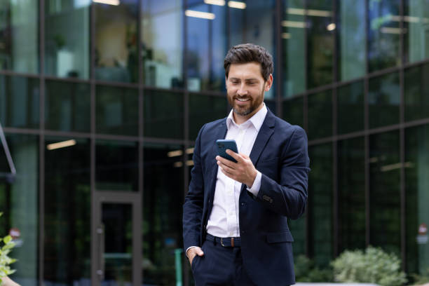 Confident businessman using smartphone in urban corporate setting, mature professional