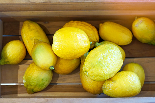 Ripe lemons in a wooden crate. The fruit is round and oval. The young fruit is green When cooked it will be yellow. The fruit flesh is juicy and sour taste.
