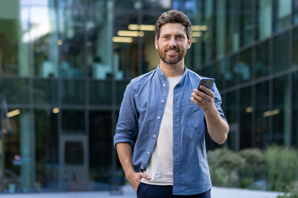 istock Confident bearded businessman using smartphone outside modern office 2030401612
