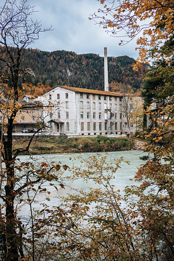 Landscape with the building of an old factory on the bank of the river in the fall