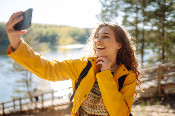 istock Cheerful female traveller holding smartphone device in hands while trekking around nature environment, 2030449442