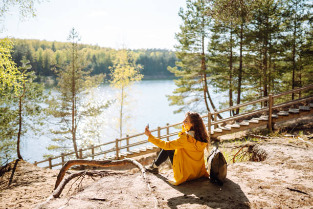 istock Cheerful female traveller holding smartphone device in hands while trekking around nature environment, 2030449446