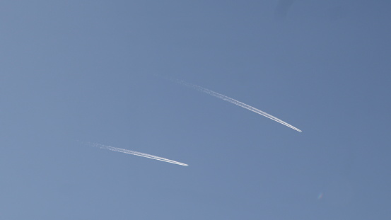 Airplane Leaving Contrail Against The Sun. Two Airplanes flying in the sky.