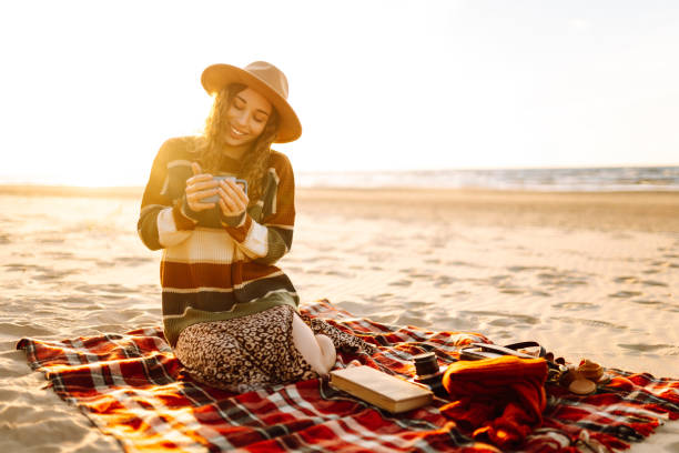 istock Young woman drinking morning coffee at picnic on the beach. 2030492425