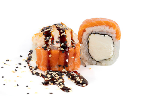 Sushi roll on a white background with Philadelphia cheese, salmon, sprinkled with soy sauce and sprinkled with sesame seeds