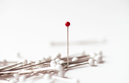 Pins on white background. Red needle.