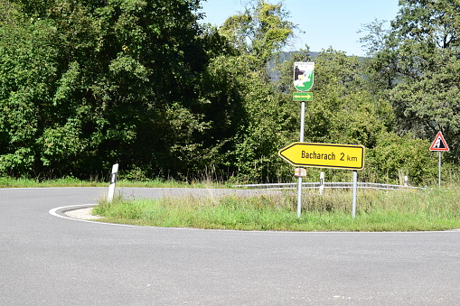 a curve mountain road with a sign to the Rhine valley town