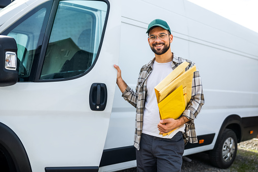 Young handsome delivery guy delivering post.