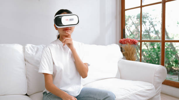 istock Young woman using virtual reality VR goggle at home for vivancy online shopping experience. The virtual reality VR innovation optimized for female digital entertainment lifestyle. 2030554856