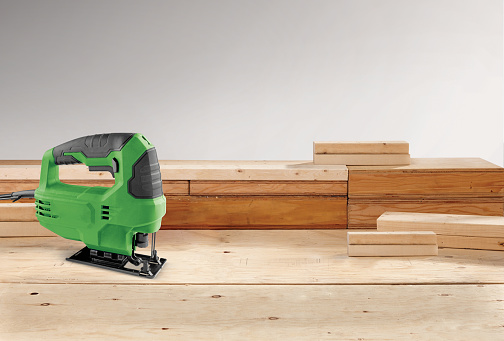 Electric jigsaw on a wooden workbench countertop background at a workshop