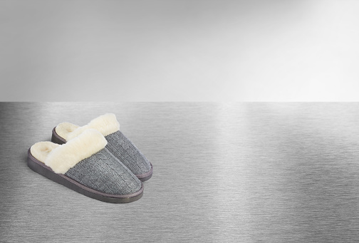 A pair of grey slippers on a metallic background