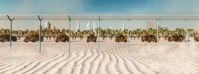 A panoramic view capturing the juxtaposition of a lush cityscape with palm trees, confined behind a stark fence on desert sands