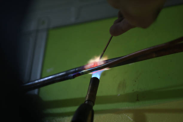 An Asian man is brazing metal prior installing air-conditioner at home.