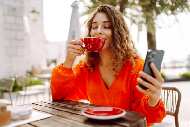 istock Smiling woman sitting with smart phone, drinking coffee on cafe. 2030582615