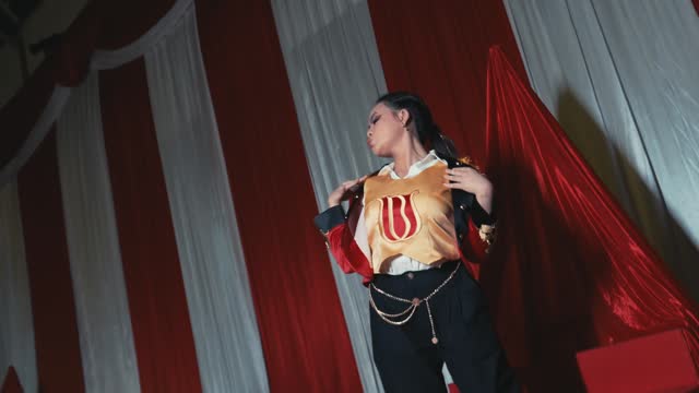 Performer in a costume on stage with red curtains and spotlight, concept of theater arts and entertainment.
