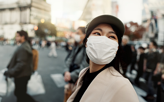 Covid, japan and woman in travel with face mask for health and on city background. Compliance, safety for wellness and female person outdoors with facial protection for corona virus pandemic