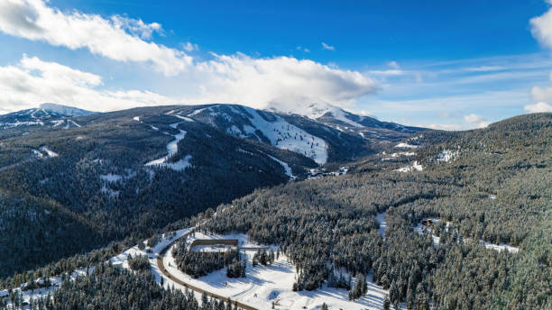 istock Road through the snowy mountains with pine trees 2030594358