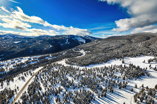 Aerial view traffic road through the snowy mountains with pine trees