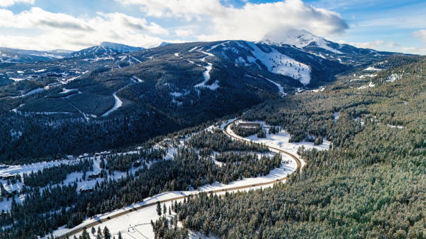 istock Road through the snowy mountains with pine trees 2030594878