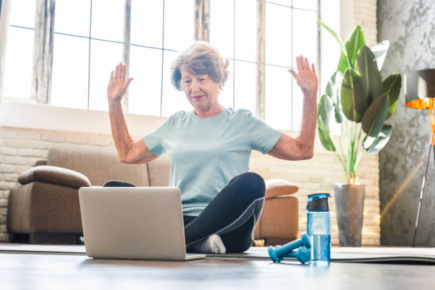 istock Senior woman doing sport at home using laptop for online tutorial. 2030608205