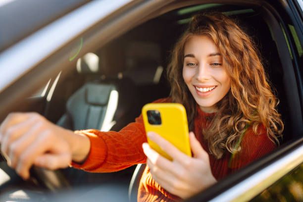 istock Young woman driver sitting in car, using smartphone. 2030623640