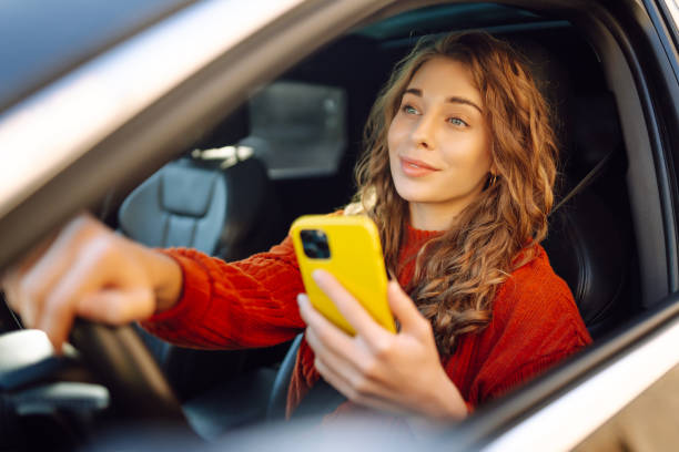 istock Young woman driver sitting in car, using smartphone. 2030623642