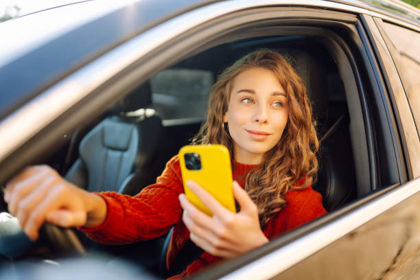 istock Young woman driver sitting in car, using smartphone. 2030623652