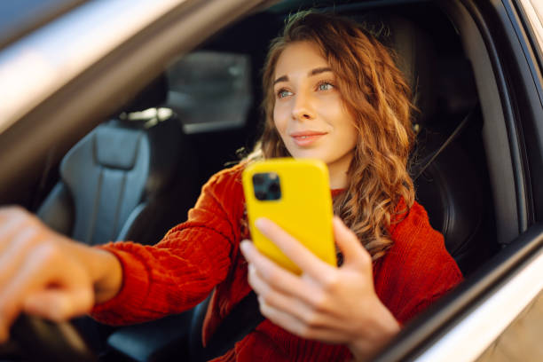 istock Young woman driver sitting in car, using smartphone. 2030623653