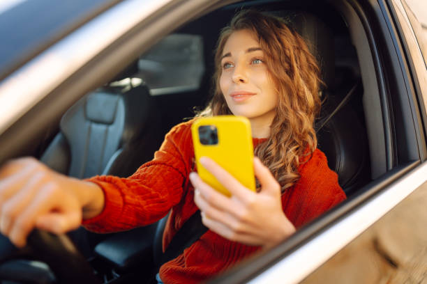 istock Young woman driver sitting in car, using smartphone. 2030623655