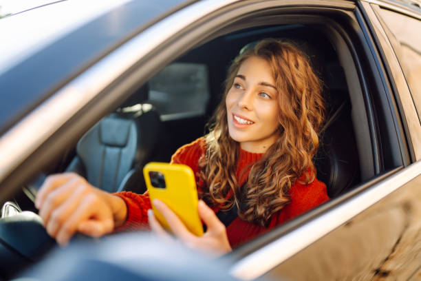 istock Young woman driver sitting in car, using smartphone. 2030623657
