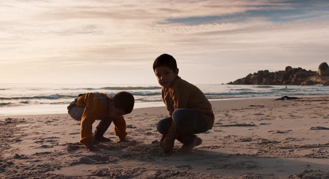 Digging, playing and children at the beach for the sand and silhouette at sunset on vacation. Morning, nature and kids or friends at the ocean for bonding, quality time or childhood on holiday
