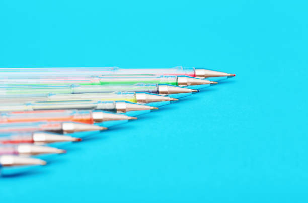 Ballpoint pens in a range of colors side by side on a blue background.