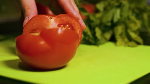 Female hands cutting tomatoes with a large kitchen knife. Close up.