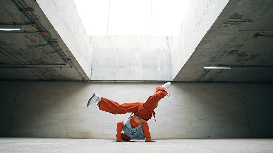 Happy dancing man enjoy practice break dance or freestyle dance in building. Professional b-boy dancer perform energetic movement or doing freeze pose modern life style. Outdoor sport 2024. Sprightly.