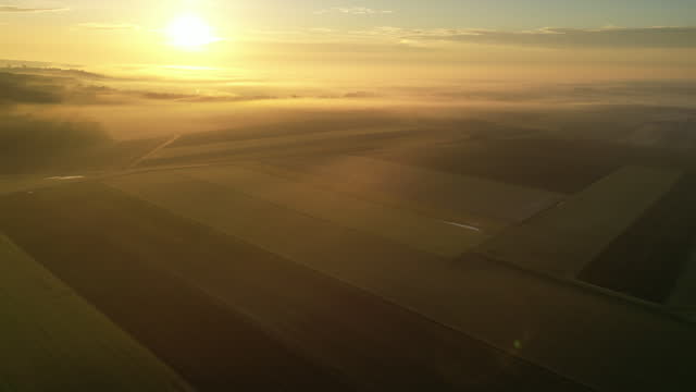 Aerial View Of Patchwork Agricultural Landscape Shrouded With Fog During Sunrise