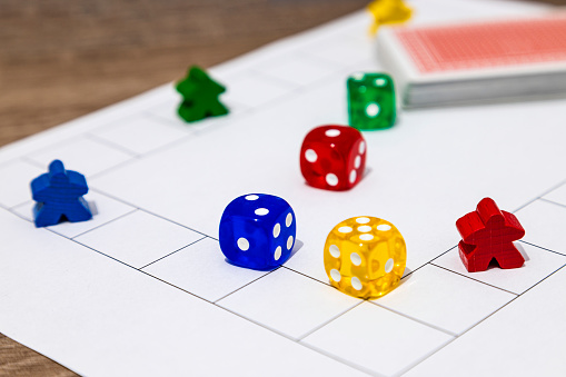 Close-up of a board game with colorful pieces and dice on a grid playfield.