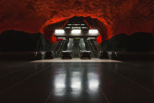 Sci fi looking dark and moody underground parking lot with fluorescent lights on.  Concrete wall