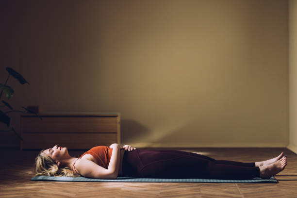 istock Woman Practicing Mindfulness in Savasana Pose on Yoga Mat Indoors 2030734092