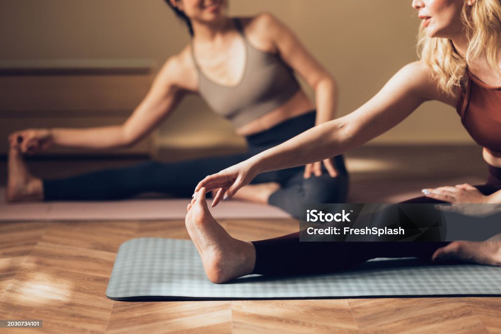 Zwei Frauen in Sportbekleidung machen Dehnübungen auf Yogamatten - Lizenzfrei Pilates-Methode Stock-Foto Zwei Frauen in Sportbekleidung machen Dehnübungen auf Yogamatten - Lizenzfrei Pilates-Methode Stock-Foto