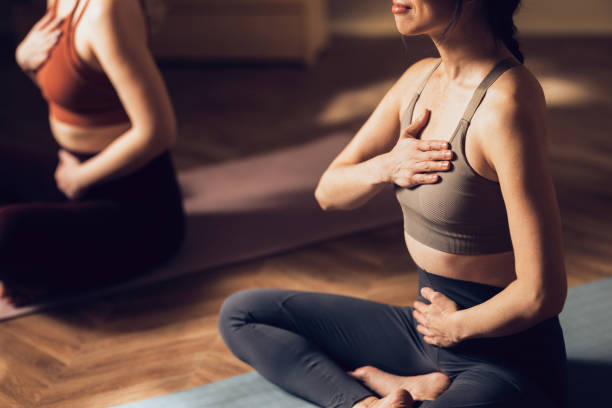 Women Practicing Yoga in a Calm Studio Environment for Wellness Two women engaging in a yoga session, focused on mindfulness and physical fitness within a tranquil studio setting. yoga meditation pose stock pictures, royalty-free photos & images