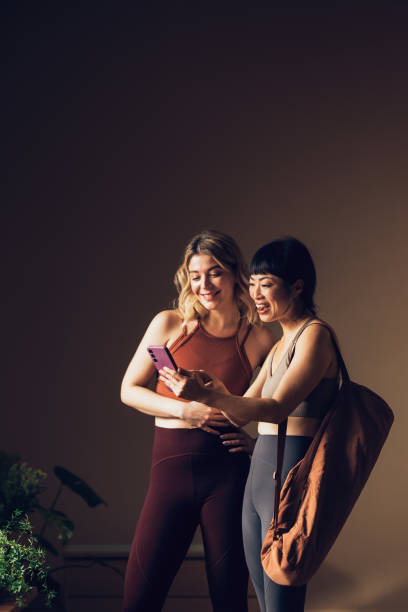 istock Two Women in Active Wear Smiling and Looking at Smartphone Together 2030735193