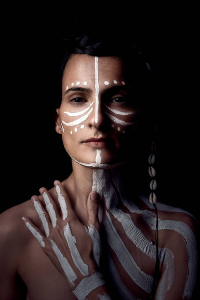 mujer étnica tranquila con rayas blancas en el cuerpo en el estudio - body studio shot looking at camera traditional culture fotografías e imágenes de stock