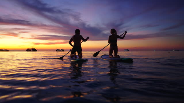 Couple paddle surfing on a beautiful beach in Koh tao