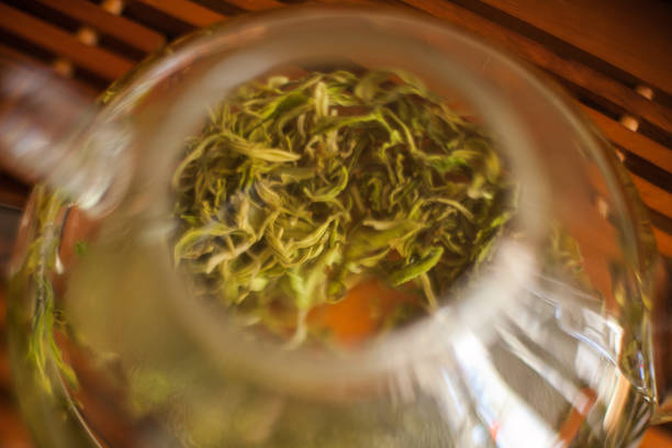 A glass bowl on the table filled with green tea leaves, a common ingredient in Chinese cuisine and often used in teainfused dishes like noodle soups