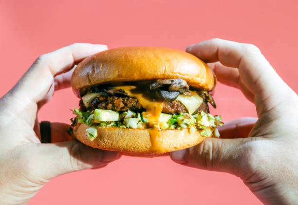 Burger held in hands with pink background